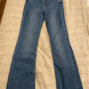 Blå flare jeans - Säljer ett par snygga blå flare jeans med hög midja. Perfekta för en trendig look med sin klassiska denimstil. Köpta från Plick. För referens är jag ca 160 och de är perfekt längd
