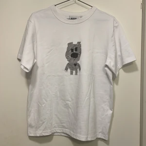 Vit t-shirt med tryck från Azzaro - Snygg vit t-shirt från Azzaro med ett unikt tryck på framsidan. Perfekt för en avslappnad stil. T-shirten har en normal passform och korta ärmar.