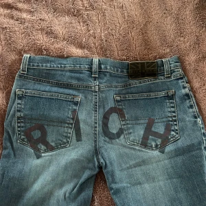 Richmond jeans med tryck - Snygga blå richmond jeans med tryck bak. Bra skick då de inte använts så mycket. Utsvängd modell, storlek 31 men passar mig som har 28/29 i vanliga fall. För långa på mig som är 163 så passar nog nån ca 170cm. Nypris ca 2500. Skulle säga strl S/M