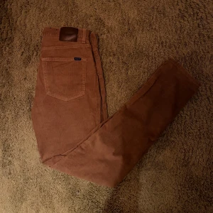 Bruna manchesterbyxor från Gant - Snygga bruna manchesterbyxor från Gant med klassisk design. Byxorna har en normal passform och är perfekta för höst och vinter. De har en läderdetalj vid midjan. Mvh C.W Closet