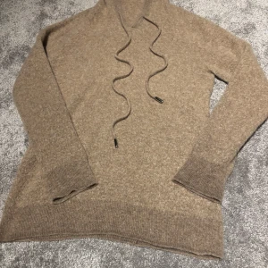 Beige hoodie - Säljer en mysig beige cashmir hoodie. Perfekt för kyliga dagar med sin mjuka och bekväma passform. Långärmad med ribbade muddar vid ärmslut och nederkant. Storlek S! Inga defekter säljer pga att den blivit för liten