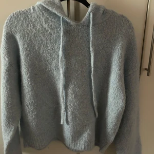 Ljusblå stickad hoodie - Jättegullig ljusblå stickad tjocktröja, endast använd en gång då jag köpte den förra veckan, tyvärr så är den för stor för mig och de är därför jag säljer den. Köpt för 400kr i butik