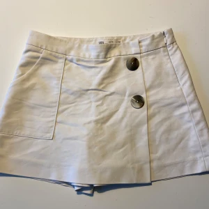 Vita shorts ifrån zara  - Säljer ett par stilrena vita shorts från Zara Kids. De har två stora knappar framtill och en enkel design utan mönster. 