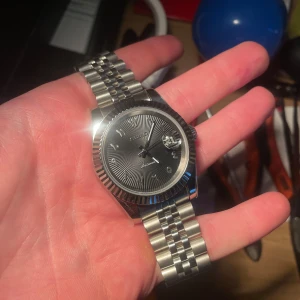 Automatic Seiko datejust - Snygg silverfärgad klocka från Seiko med ett klassiskt armband i rostfritt stål. Urtavlan är svart med arabiska siffror och datumvisning. Perfekt för den stilmedvetna!
