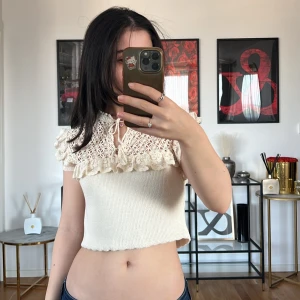 Beige stickad topp med spetsdetaljer Zara - Säljer en superfin beige stickad topp från Zara med vackra spetsdetaljer och volang vid axlarna. Toppen är croppad och har en söt knytning framtill. Perfekt för sommardagar eller en festlig kväll!💓