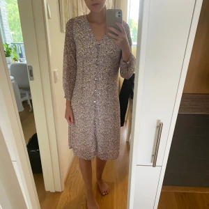 Blommig klänning  - Lila & beige blommig klänning från Vero Moda i storlek XS, men skulle även säga att den passar som en S. Knappar framtill. Jag är 165 cm lång. Endast använd ett fåtal gånger.