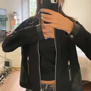 Svart jacka från Pulz - Säljer en snygg svart jacka från Pulz. Den har en dragkedja framtill och två fickor med dragkedjor. Jackan har långa ärmar och en stilren design, perfekt för både vardag och fest. Insidan är fodrad med ett ljust tyg.