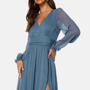 Balklänning  - En vacker blå klänning med långa ärmar och en v-ringning. Klänningen har en smal midja och en vid kjol. Den är perfekt för en fest eller ett bröllop. Använd 1 gång!