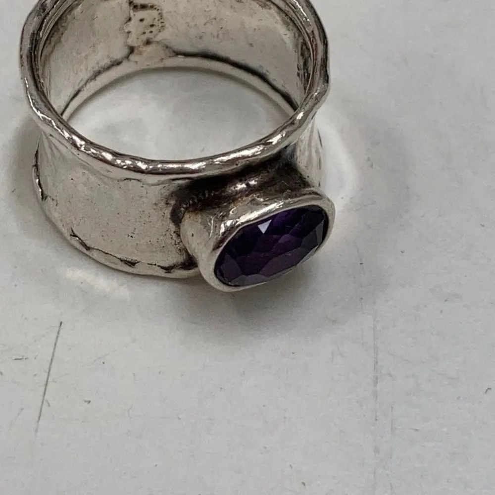 Säljer en unik och stilren silverring med en vacker lila sten i mitten. Ringen har en bred design med en rustik finish som ger den en cool och modern look. Perfekt för att ge lite färg till din outfit. 16 3/4 mm.. Accessoarer.