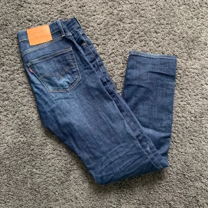 Blå jeans från Levi's - Säljer ett par klassiska blå jeans från Levi's. De har en snygg och tidlös design med fem fickor och en knappgylf. Jeansen är i bra skick och har en bekväm passform. Perfekta för både vardag och fest!