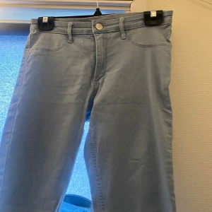 Ljusblå skinny jeans - Säljer ett par ljusblå skinny jeans i denim. De är i storlek EUR 164 och passar perfekt för en ungdom. Jeansen har en klassisk femficksdesign och en knapp med dragkedja framtill. Perfekta för vardagsbruk!