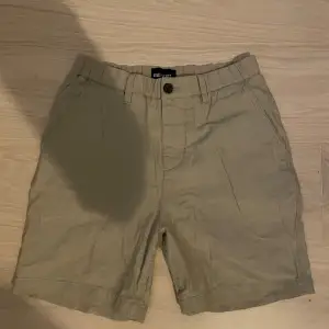 Säljer ett par snygga beige shorts från Lyle & Scott. De har en klassisk design med knapp och dragkedja framtill. Två fickor bak med en liten logga på ena sidan. Perfekta för sommaren!