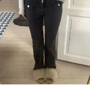 Svarta byxor med knappar - Säljer ett par snygga svarta byxor med vita knappar. De har en bootcut-stil och ser ut att vara högmidjade. Perfekta för både vardag och fest!