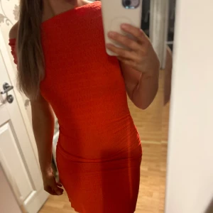 Röd offshoulder klänning - Säljer en superfin röd offshoulder klänning som sitter tight och framhäver figuren. Perfekt för festliga tillfällen! Klänningen är axelbandslös och har en smickrande passform. Den är i ett stretchigt material som gör den bekväm att bära hela kvällen.