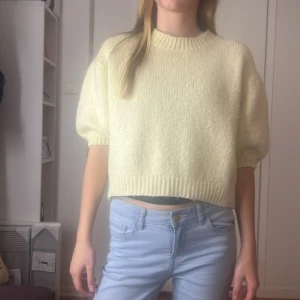 Gul stickad croppad tröja - Säljer en superfin gul stickad tröja som är croppad och perfekt för vår och sommar. Den har en normal passform med korta ärmar och ribbade kanter. Tröjan är både mysig och stilren, perfekt att matcha med jeans eller kjol!