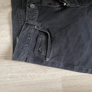 Svarta jeans från J.Lindeberg - Säljer ett par snygga svarta jeans från J.Lindeberg. De har en klassisk femficksdesign med en diskret logga på fickan, endast provade. Står 29/32 men skulle nog mer säga 28/30.