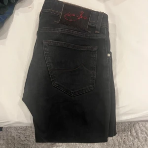 Jacob cohen jeans - - Svarta jacob cohen jeans med röda och bruna detaljer - Storlek 31 / Model 622 slimfit - Skick 9/10 som nya nästan - Endast jeansen medföljer - 100% äkta