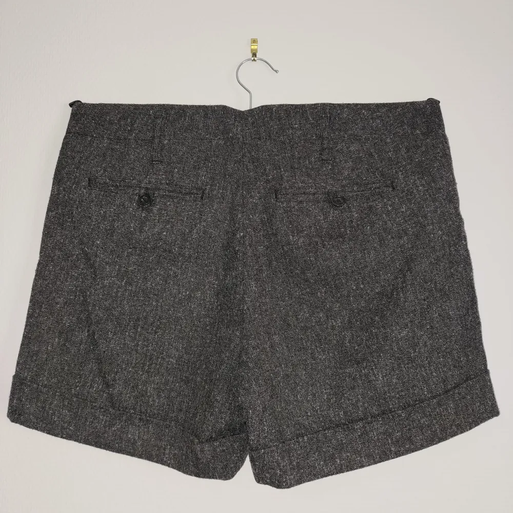 Säljer ett par stilrena grå shorts med uppvikta ben. De har en klassisk look med två fickor bak och en diskret dragkedja fram. Perfekta för en avslappnad men ändå snygg stil.. Shorts.