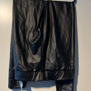 Svarta skinnbyxor - Säljer ett par snygga svarta skinnbyxor. De har en stilren och modern look, perfekt för både fest och vardag. Byxorna är i nyskick och har en tight passform som framhäver benen. Perfekta för höst och vinter!