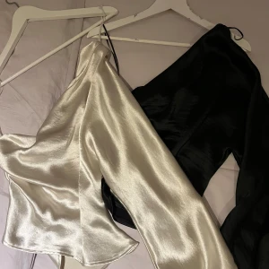 2 st one shoulder tröjor i satin - ginatricot - 2 st. one shoulder tröjor i satin, svart och vit. Bägge är från ginatricot och den svarta är helt oanvänd. Den vita är endast använd 1 gång, som ny. Bägge är i storlek 38.