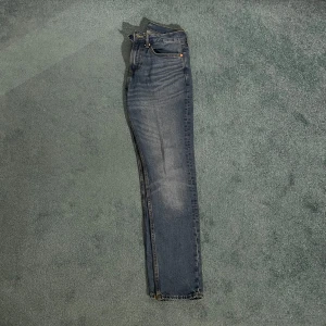 Blå slim jeans från H&M - Säljer ett par snygga blå slim jeans från H&M. De har en klassisk femficksdesign och är i en stilren blå färg med lätt slitna detaljer för en cool look. Perfekta för både vardag och fest!