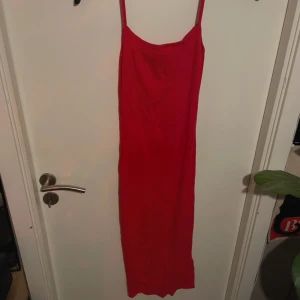 Röd långklänning med smala axelband - Säljer en elegant röd långklänning med smala axelband. Perfekt för festliga tillfällen eller en utekväll. Klänningen har en enkel och stilren design som framhäver figuren. Passar bra till både sommar och nyår.