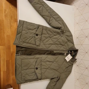 Barbour mörkgrön jacka, storlek M - En Barbour jacka i en mörkgrön färg. Jackan har en dragkedja framtill och två fickor på framsida.Skriv gärna om du vill ha fler bilder eller information.Se gärna övriga auktioner. Titta gärna på bilderna för egen bedömning 