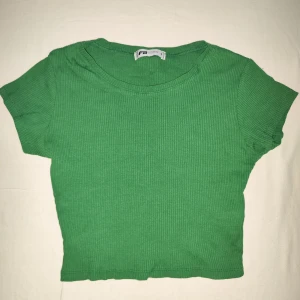 Grön ribbad crop topp från FB Sister - Säljer en superfin grön ribbad topp från FB Sister i storlek S. Den är kortärmad och croppad, perfekt för sommardagar eller en avslappnad look. Toppen är i bra skick och har en skön passform. Perfekt att matcha med jeans eller kjol! 💚