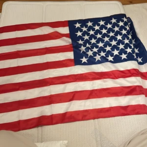 Amerikansk flagga - Stor amerikansk flagga med de klassiska röda och vita ränderna samt vita stjärnor på blå bakgrund. Perfekt för dekoration eller samling.