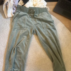 Gröna mjukisbyxor från Juicy Couture - Snygga gröna mjukisbyxor från Juicy Couture med snörning i midjan och praktiska fickor. Perfekta för en avslappnad stil.