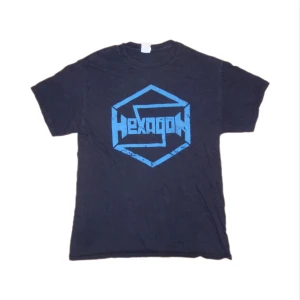 Svart t-shirt med blå Hexagon-logga - Snygg svart t-shirt med en stor blå Hexagon-logga på framsidan. Perfekt för en avslappnad stil. T-shirten har korta ärmar och en klassisk passform.