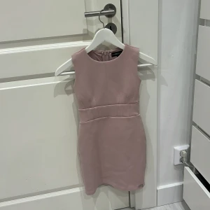 Guess klänning - Snygg ljusrosa klänning med en figurnära passform. Den är ärmlös och har en diskret dragkedja i ryggen. Perfekt för en stilren look. Denna är köpt på barnavdelningen 