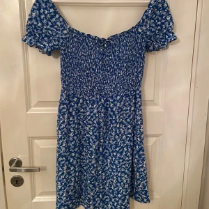 Blå klänning i ett fjärilstyg/ blommigt  - Charmig blå klänning med ett fjärilsmönster från New yorker. Klänningen har korta puffärmar och en liten knytning framtill. Perfekt för sommarens varma dagar. I storlek S 🌸I ett fint skick ⭐️