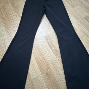 Svarta kostymbyxor från Vero Moda - Snygga svarta byxor från Vero Moda med en klassisk design. Byxorna har en bootcut-stil och är tillverkade i ett bekvämt material. Perfekta för en stilren look. Använd 1-2 gånger och är i strl xs