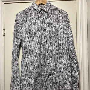 Mönstrad skjorta från Emilio - Snygg långärmad skjorta från Emilio med ett unikt mönster i blått och vitt. Skjortan har knappar framtill och en klassisk krage. Perfekt för att ge din outfit en stilfull touch.