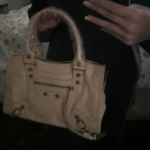 Balenciaga liknande väska - Snygg beige handväska med dragkedja och dekorativa nitar. Mellan storlek så de får plats mycket. Kom privat för frågor