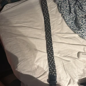 Flätat bälte från Onewear - Snyggt flätat bälte från Onewear i svart, blå och grått. Perfekt för att ge en stilren touch till din outfit. Bältet har en klassisk design med ett robust spänne.