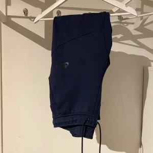 Mörkblåa Nike tech byxor - Tjenare säljer mina Nike tech byxor då de inte används längre och har blivit för små. Jättesköna vardagsbyxor med en större ficka på sidan med dragkedja. Inga skador eller liknande. Skriv för frågor och priset är ej hugget i sten