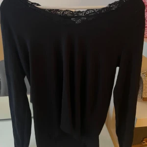 Svart långärmad topp med spetsdetalj - Elegant svart långärmad topp med spetsdetalj vid halsringningen. 
