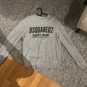 Grå sweatshirt från Dsquared2 - Säljer en stilren grå sweatshirt från Dsquared2 med tryck 'Ceresio 9, Milano' på framsidan. Tröjan har långa ärmar och en klassisk rund halsringning. Perfekt för en avslappnad look. Hade kunnat gå ner i pris vid en snabb och enkel affär. Knappt använd endast ett par gånger