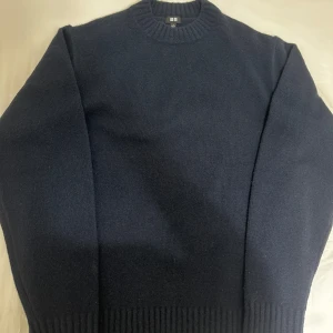 Mörkblå stickad tröja från Uniqlo. Oanvänd! - Säljer en stilren mörkblå stickad tröja från Uniqlo. Tröjan har en klassisk rund halsringning och ribbade muddar vid ärmslut och nederkant. Perfekt för kyligare dagar. Har aldrig använt den. Jätte mjuk och skön. Den passar med mycket.