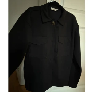 Kappa - Svart Kappa med två fickor, inte använd