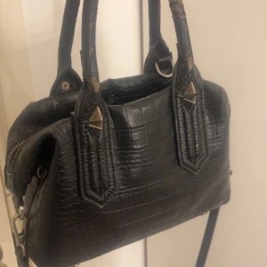 Svart krokodilpräglad handväska - Jätte fin handväska, den är väll andvänd så den har ganska mycket slitningar där man ”håller” i väskan(därav priset) Kom privat för fler bilder.🙌🏼