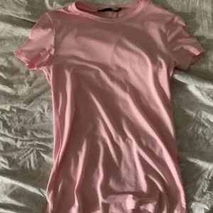 Rosa t-shirt - Säljer en enkel och stilren rosa t-shirt med korta ärmar. Perfekt för en avslappnad look.