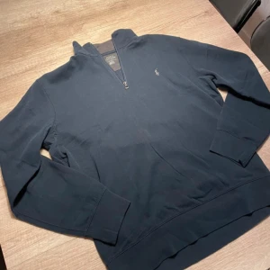 Ralph lauren half zip - Snygg mörkblå tröja från Ralph Lauren med halv dragkedja och broderad logga på bröstet. Perfekt för en stilren och avslappnad look. .