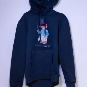 Ralph Lauren Hoodie - Helt ny Ralph Lauren Hoodie med en ikonisk nallebrodyr på framsidan. Hoodien har en klassisk passform med justerbar huva och en praktisk magficka. Perfekt för en avslappnad stil. Fler storlekar finns i min profil😊
