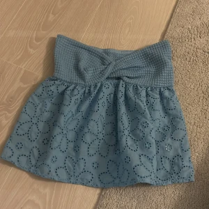 Blå tubtopp - Tubtoppp med ett vackert blommönster och en ribbad midja. Kjolen har en volangdetalj och är perfekt för en somrig look.