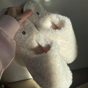 Vita fluffiga tofflor - Mysiga vita tofflor med fluffigt material, perfekta för att hålla fötterna varma. Cremefärg.