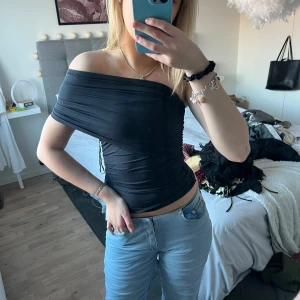 Svart offshoulder topp - Snygg svart offshoulder topp med tight passform. Perfekt för en stilren look. Toppen har en elegant design som framhäver axlarna.