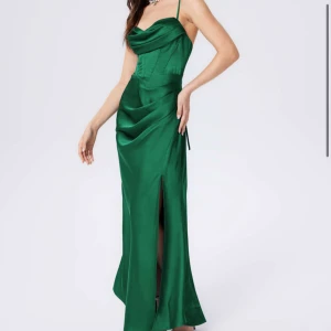 Grön långklänning med slits - Elegant grön långklänning med smala axelband och en stilren slits framtill. Klänning är i storlek L-XL och aldrig kommit till användning!